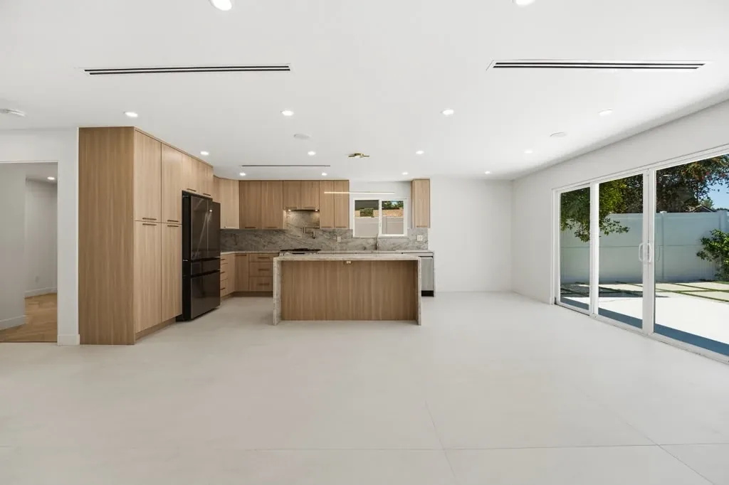 Interior of a completed garage conversion by Yeganeh Inc., with a kitchen, open living area and sliding doors to the yard