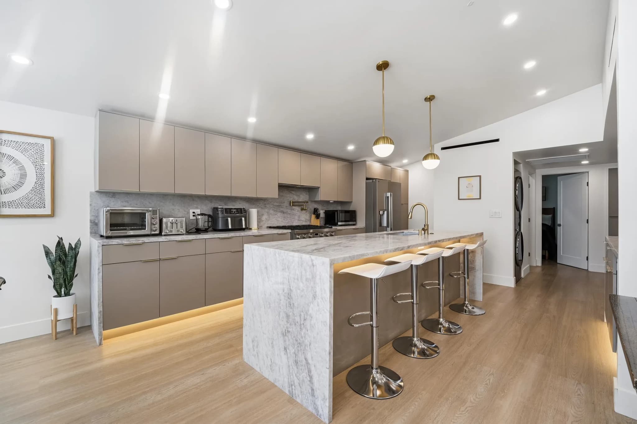 Kitchen at the Kentland project with a stone waterfall island, pendant lighting and full-height cabinetry