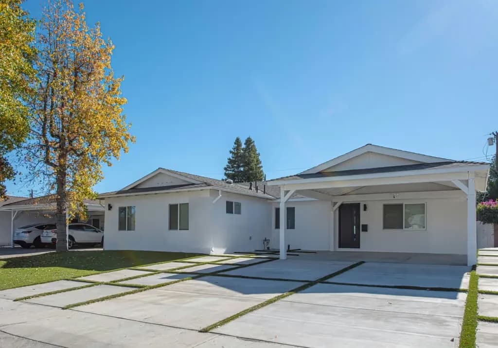 Exterior of the Kittridge project by Yeganeh Inc., showing the remodelled single-storey house with a new carport and banded hardscape