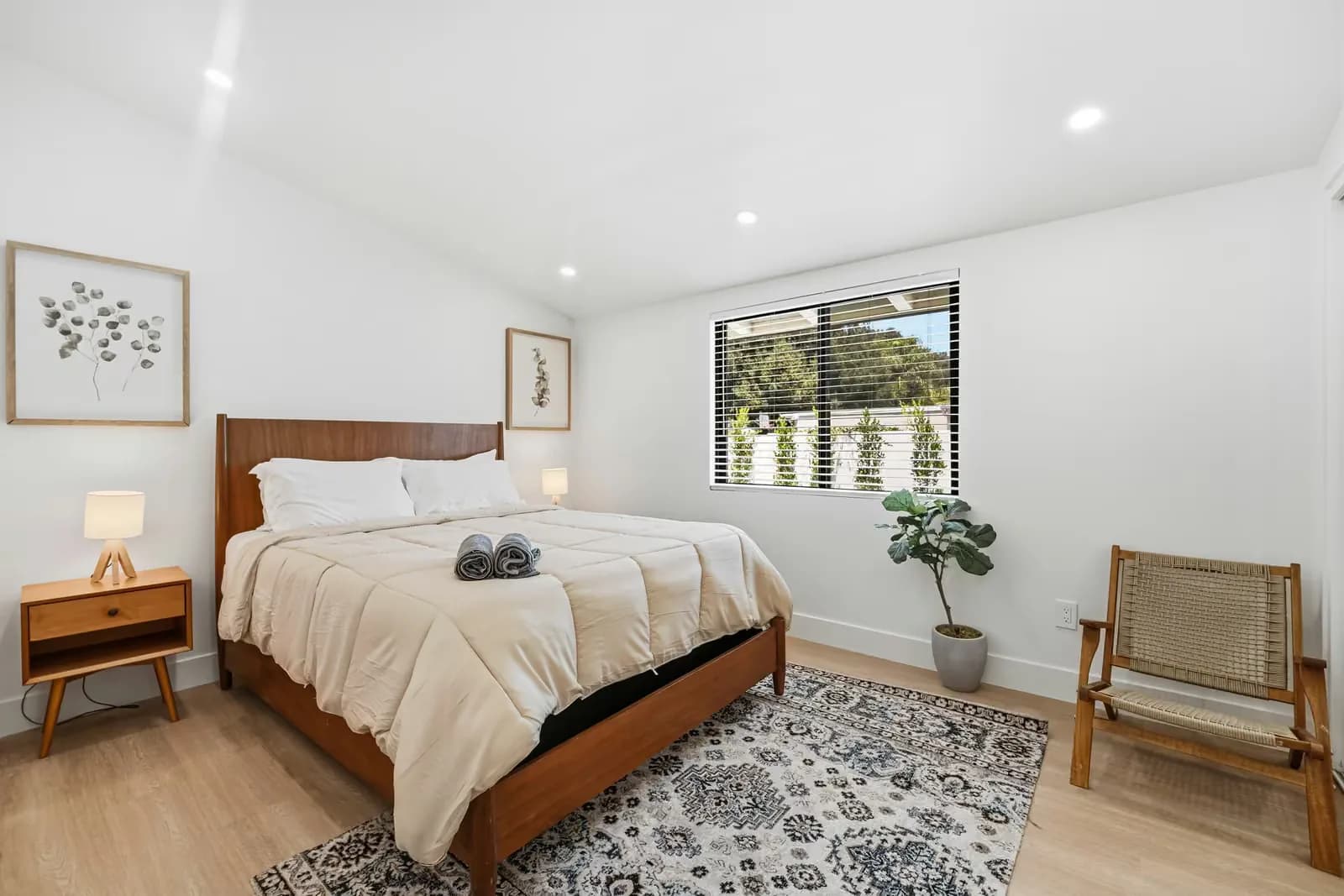 ADU bedroom with a vaulted ceiling, framed prints and a rug over wood flooring