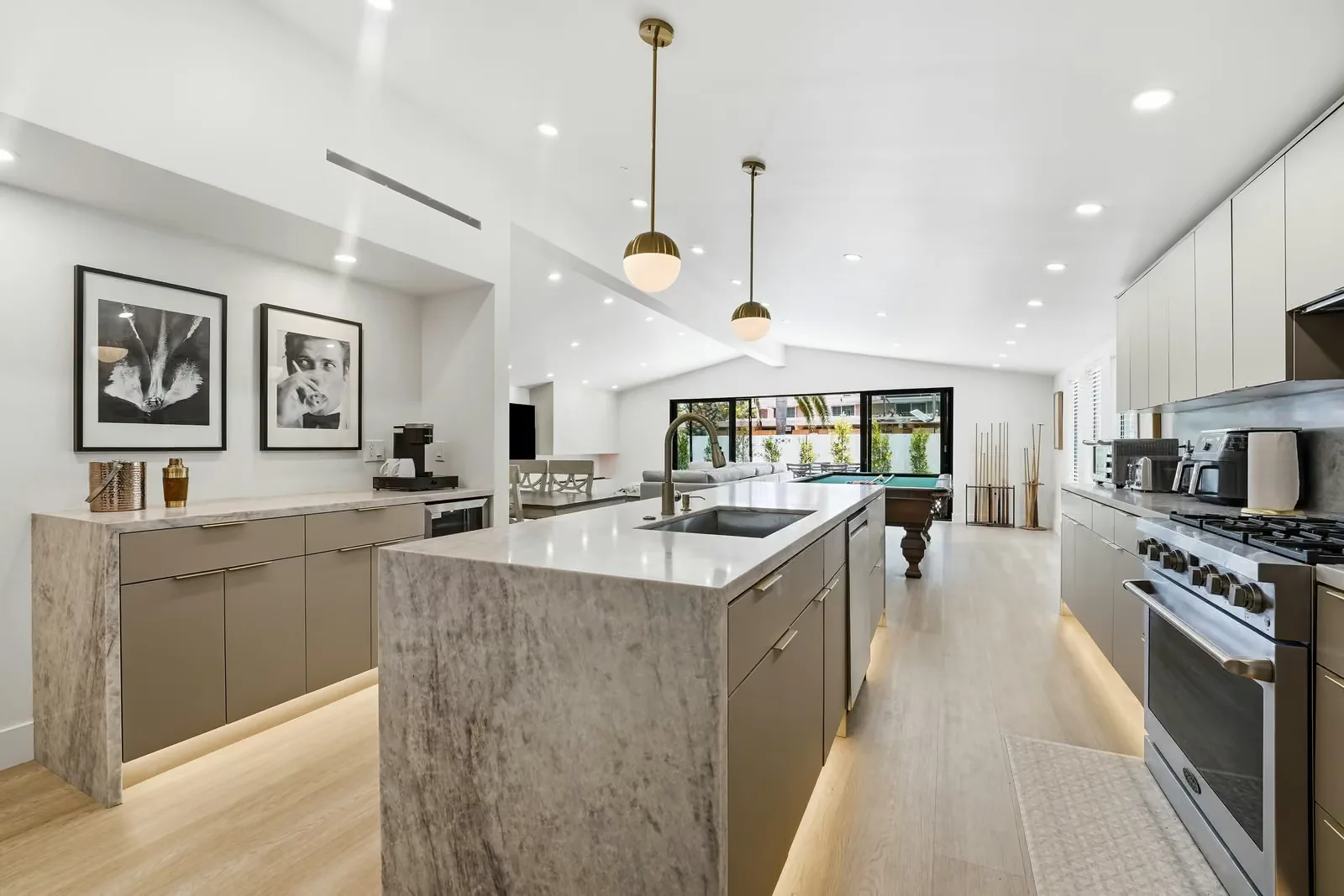 ADU kitchen with a stone waterfall island, pendant lighting and a vaulted ceiling