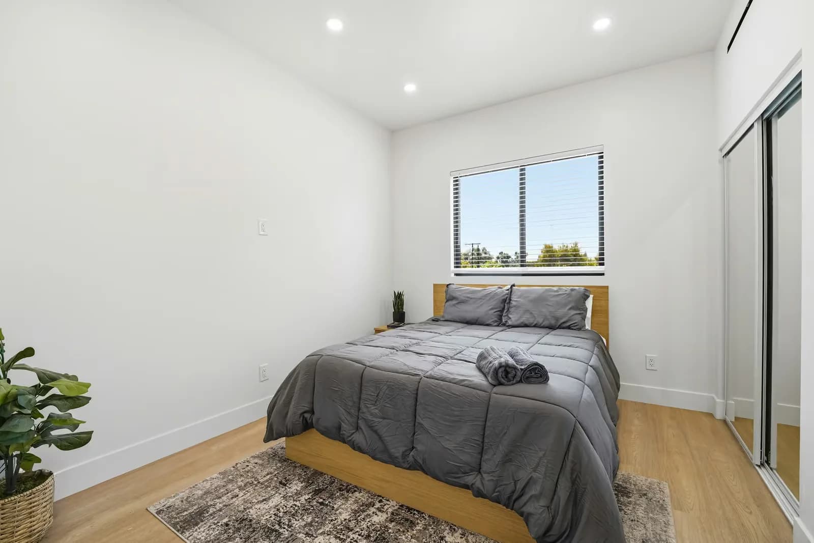 ADU bedroom with a vaulted ceiling, wood flooring and a window onto the yard