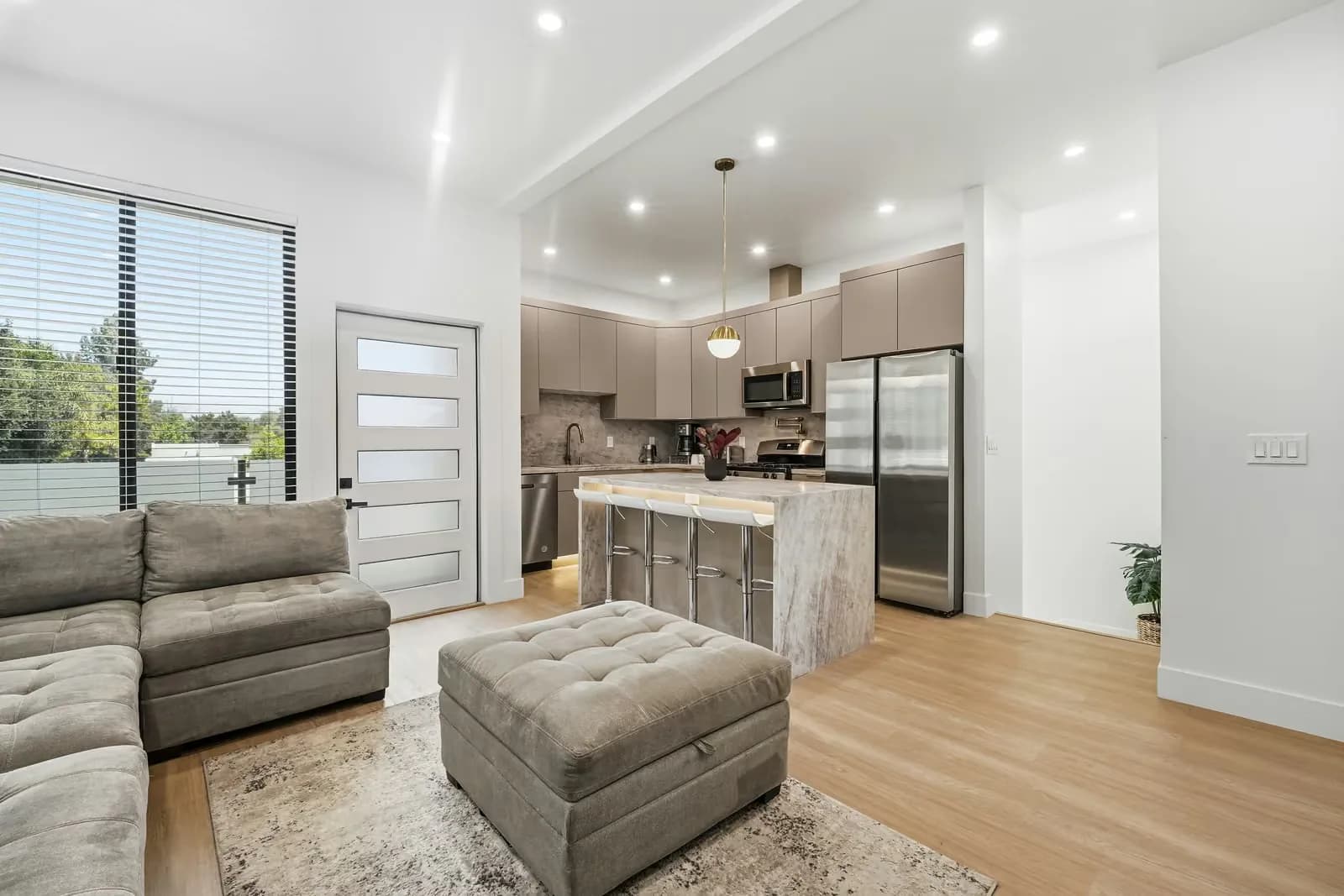 ADU living area opening onto a kitchen with a stone island and stainless appliances