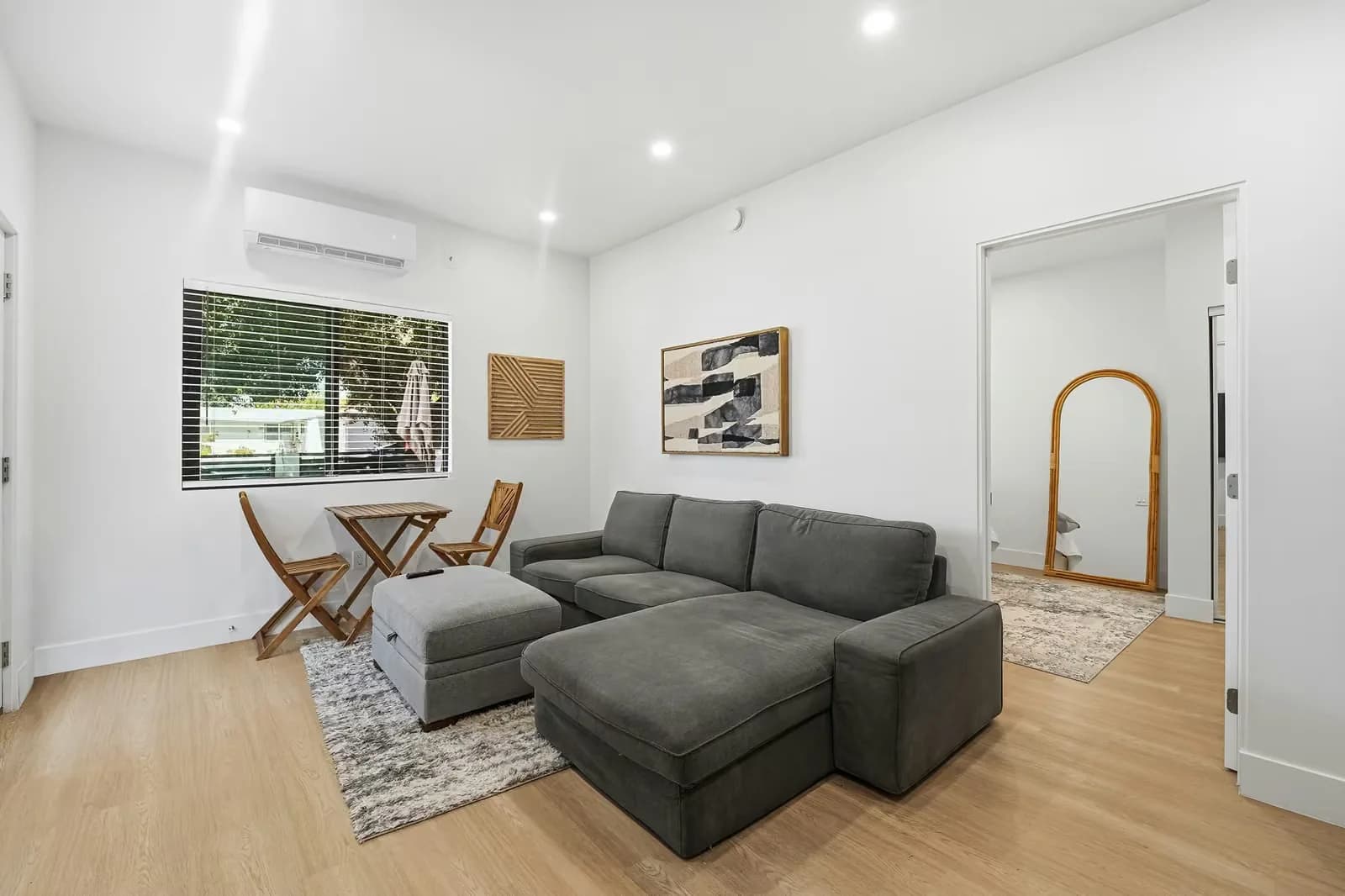 ADU living area with a wall-mounted air conditioning unit and a view through to a bathroom