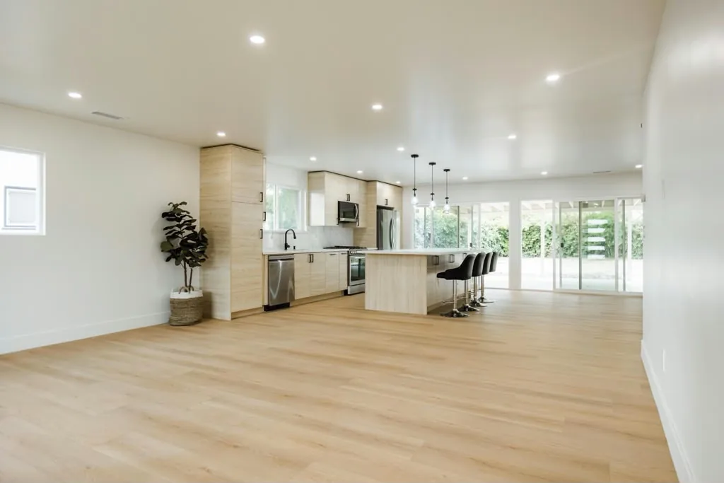 Open-plan living area and kitchen in the Sausalito project by Yeganeh Inc., with light wood flooring and glass doors to the garden