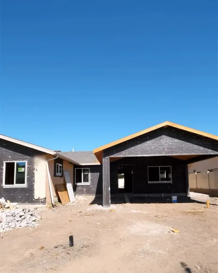 Home mid-construction with exposed roof framing and weather barrier on a Yeganeh Inc. job site